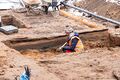 Im Schnitt gut zu erkennen: der Bohlenweg aus Holz, darunter weitere ehem. Straßen aus der Vergangenheit. Archäologische Ausgrabungsarbeiten in der Würzburg Straße in Burgfarrnbach, Dez. 2023